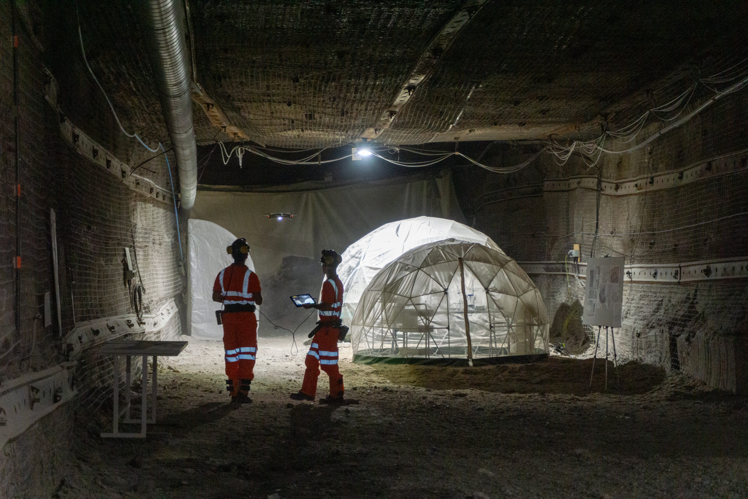 Two researchers flying a drone in one of the underground tunnels
